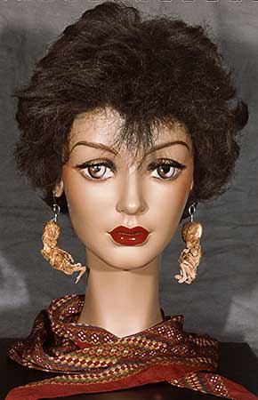 Colour police photograph of front view of mannequin head wearing human foetus earrings with a scarf covering the mannequin's neck