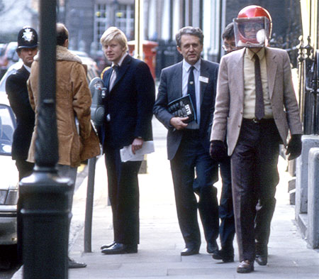 Colour photo of, from left to right, a policeman, a journalist, Boris Johnson, two unidentified men and Rick Gibson wearing rat helmet