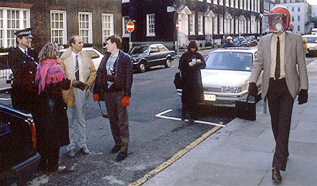 Colour photo of people laughing while Rick Gibson walks back and forth with rat helmet