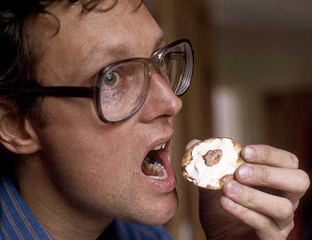 Colour photo of Gibson holding human tonsil hors d'oeuvre outside his mouth
