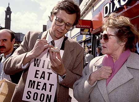 Color photo of Gibson showing the meat hors d'oeuvre to a woman