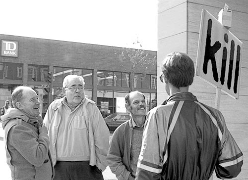 Black and white photo of Gibson talking with three men