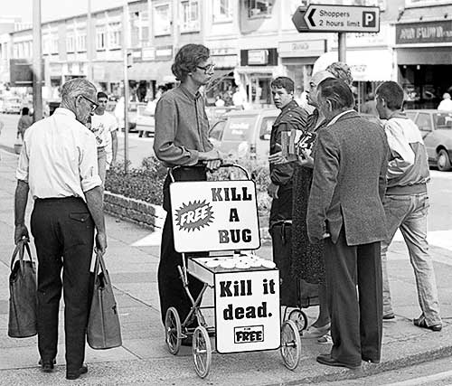 PICTURE: black and white photo of Gibson talking with Ms. Piddington and a man who wants to kill an insect.  Pedestrian shoppers look on.
