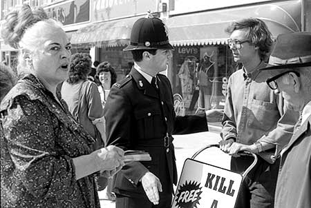 PICTURE: black and white photo of policeman arresting Gibson while Ms. Piddington and a pedestrian watch.