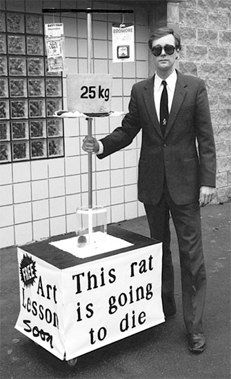 PICTURE: black and white publicity photo of Gibson standing beside the rat crushing art machine.