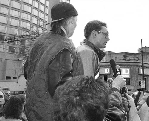 PICTURE: black and white photo of Susi and Gibson standing on a street planter and overlooking the crowd